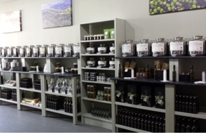 Interior of a specialty olive oil store with stainless dispensers and rows of bottles on dark wooden shelves